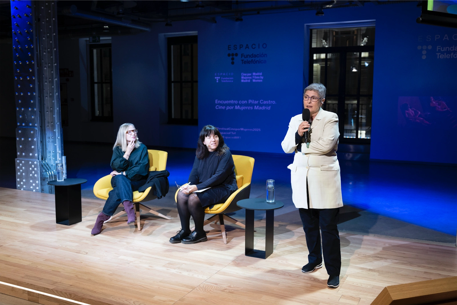 María Adell y Pilar Castro escuchan atentamente durante una charla en un evento.