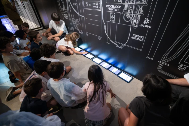 Un grupo de niños recorrre la exposición 'Revolución Cuántica' en un taller sobre cuántica