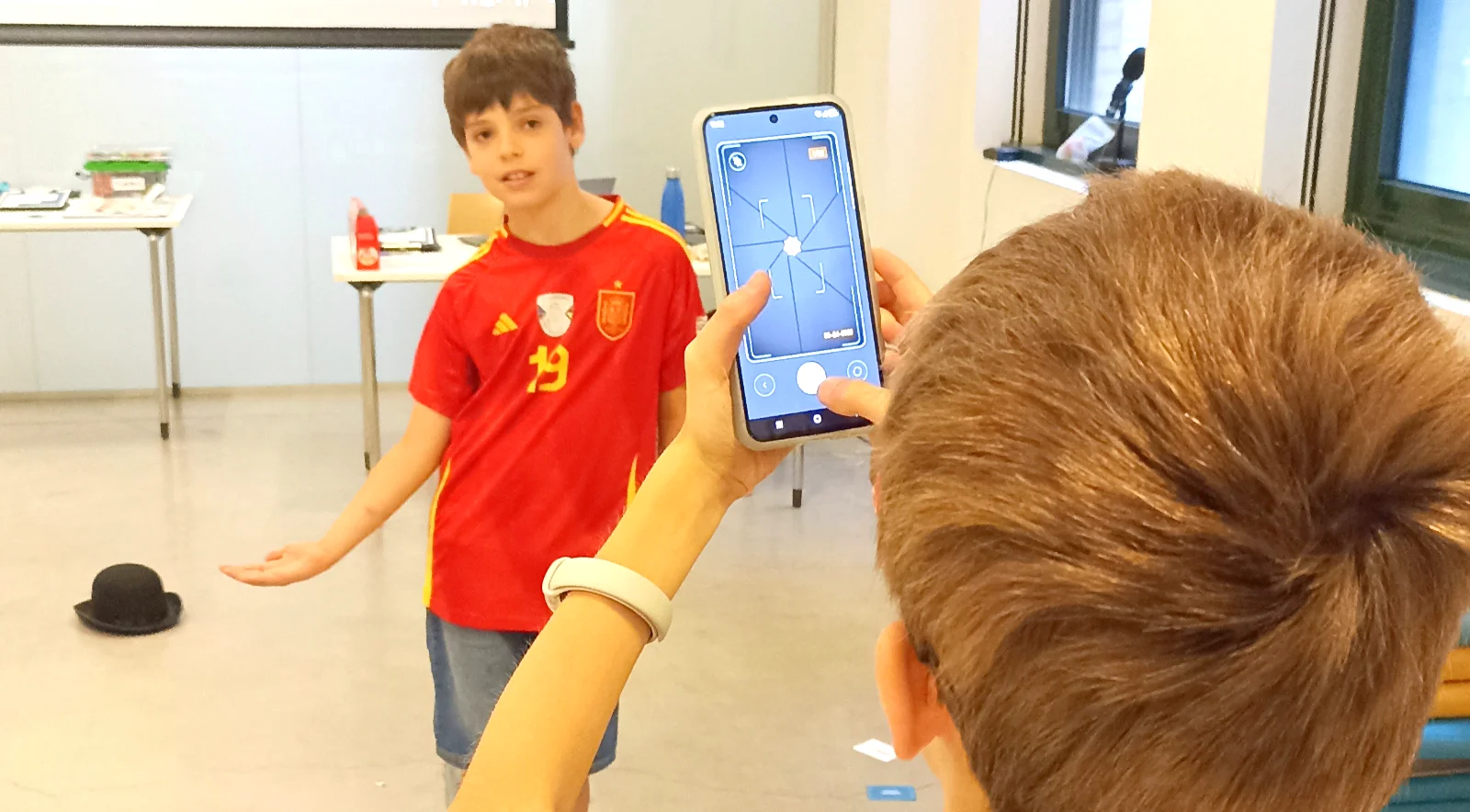 Dos niños experimentan con la cámara de un móvil en un taller de fotografía